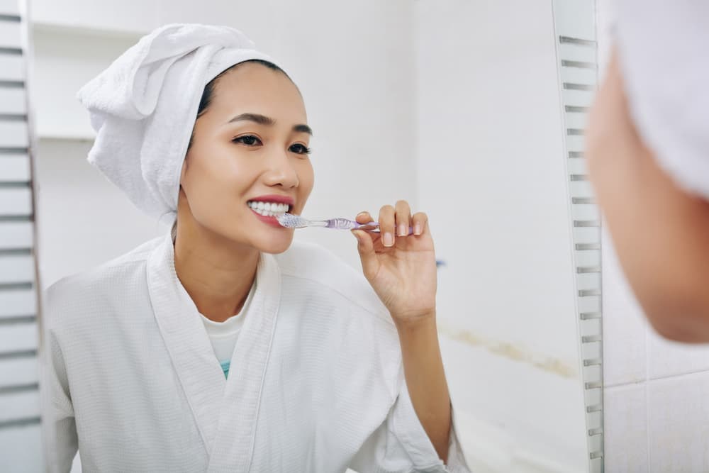 young-woman-brushing-teeth-W8UT7RJ (1)